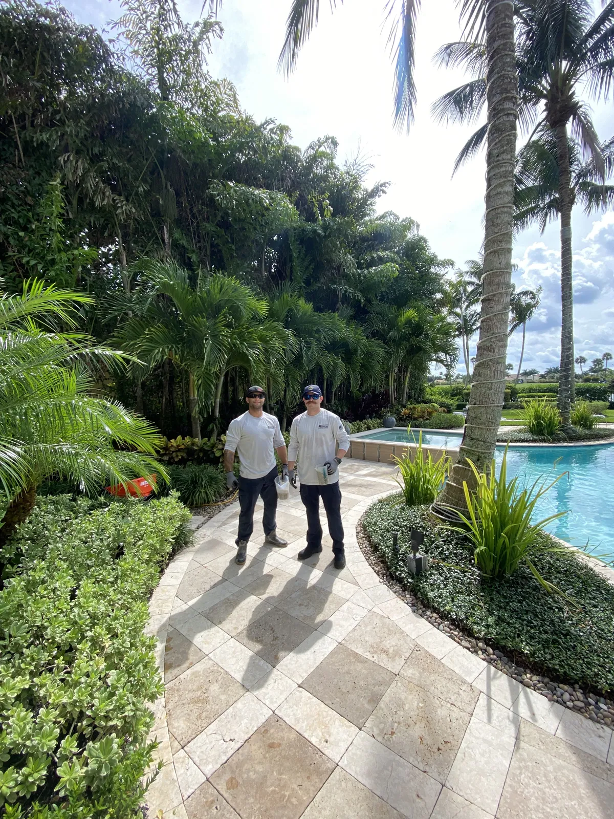 Two Frontline Pest Control technicians on a pool walkway at a client property