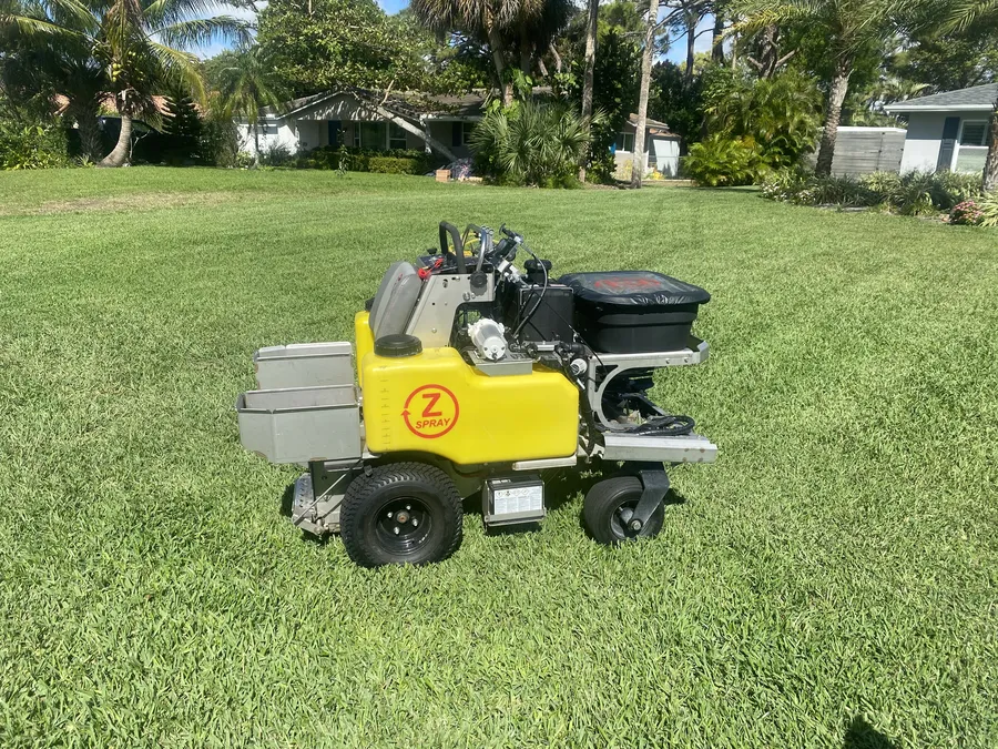Ride-on spreader applying fertilizer to a lawn